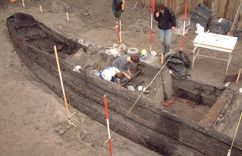 Informatiebijeenkomst-Werelderfgoednominatie-Limes-romeins-schip-opgraving Opgraving van het Romeinse schip. Twee archeologen zitten in de boot en een staat ernaast.