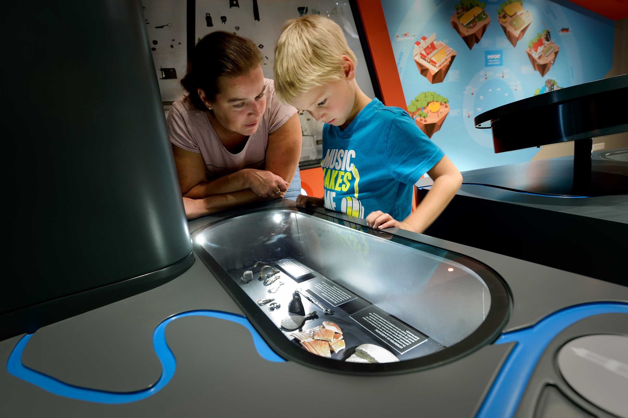 Moeder en kind bekijken een stuk binnen de interactieve expositie bij Museum Hoge Woerd