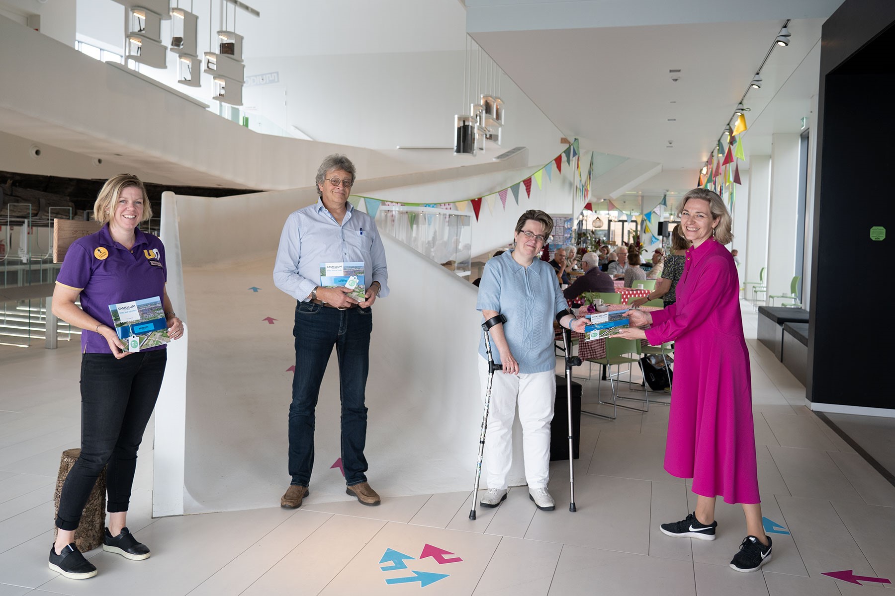Wethouder Anke Klein reikt museumgids uit aan vrijwilligers