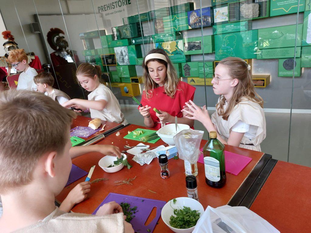 Houd jij van koken en ben je niet bang om nieuwe smaken te proeven? Kom dan naar de workshop 'Romeinse Smulpapen'! We gaan aan de slag met recepten uit een echt Romeins kookboek van de beroemde kok Apicius.
Vroeger aten de Romeinen heel anders dan wij. Rijke Romeinen lagen op sofa's te eten en gebruikten hun handen in plaats van een vork. Ze hielden van kruidig, zuur en zoet. Wist je dat ze zelfs peper op hun zoete koekjes strooiden? En dat zij de kip naar Nederland hebben gebracht?
Samen maken we een paar heerlijke Romeinse gerechten die je natuurlijk ook zelf mag proeven. Ouders en begeleiders zijn ook van harte welkom om mee te helpen en te smullen!