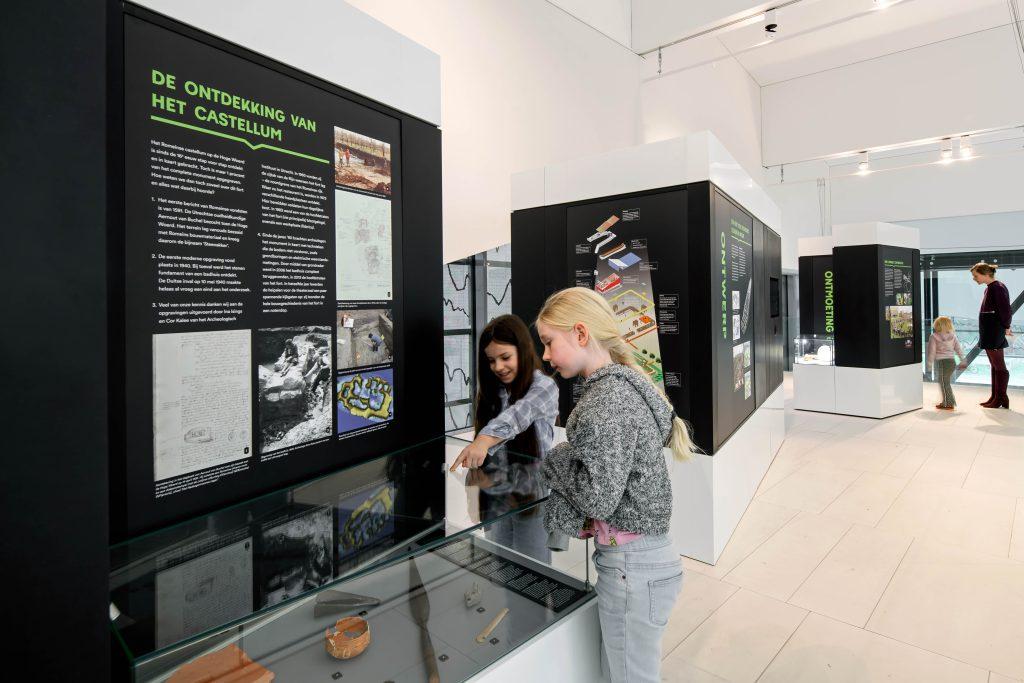Hoe weet je dat er onder je voeten ooit een Romeins fort stond? En hoe vertaal je dat verleden naar een modern gebouw dat vandaag de dag bovenop UNESCO‑Werelderfgoed staat? In de tijdelijke tentoonstelling Creatie van het Castellum ontdek je stap voor stap hoe archeologen, onderzoekers en ontwerpers samen het verhaal van de Hoge Woerd hebben ontrafeld.

Je volgt het spoor vanaf de eerste aanwijzingen in de bodem, via de herkenning van het fort en de reconstructie van zijn vorm, tot aan het ontwerp van het huidige Castellum. De expositie laat zien hoe vondsten, kaarten, bodemsporen en historische kennis samenkomen om een verdwenen fort opnieuw zichtbaar te maken.

Maar het verhaal stopt niet in het verleden. Je ziet ook wie het Castellum nu gebruiken en bezoeken: van museum en theater tot horeca, buurtbewoners en jonge ontdekkers. Zo wordt duidelijk hoe geschiedenis, onderzoek en architectuur elkaar versterken op deze unieke plek.

Creatie van het Castellum is een compacte, toegankelijke tentoonstelling die laat zien hoe een Romeins fort opnieuw tot leven kwam én hoe het vandaag de dag midden in de samenleving staat.